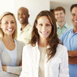 A group of five people in smart clothing smile at the camera