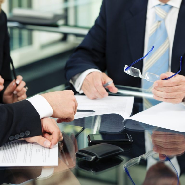 Office Environment: People sat at a table in an office environment, consulting paperwork